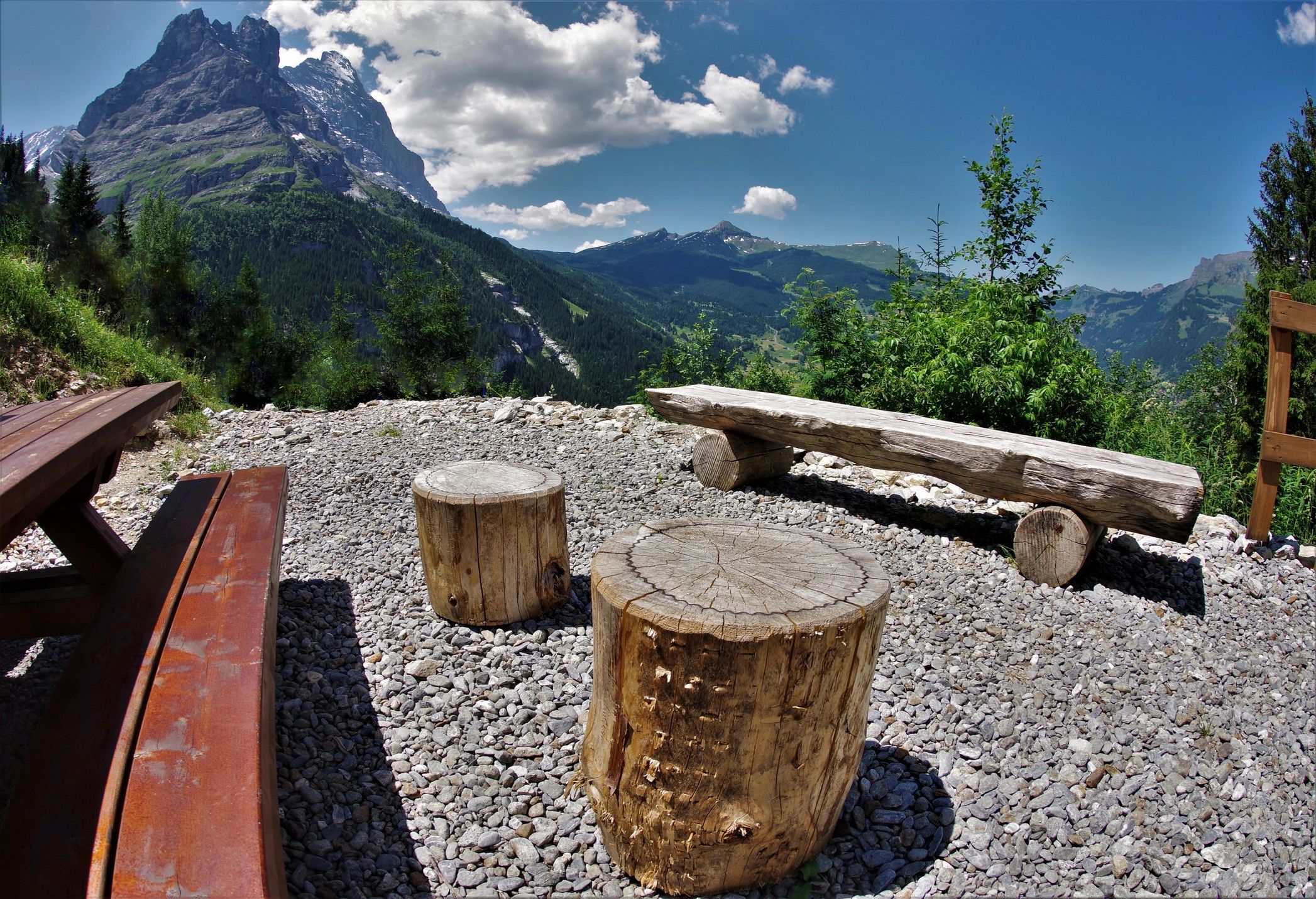 Mountain campfire site with picnic tables and alpine scenery
