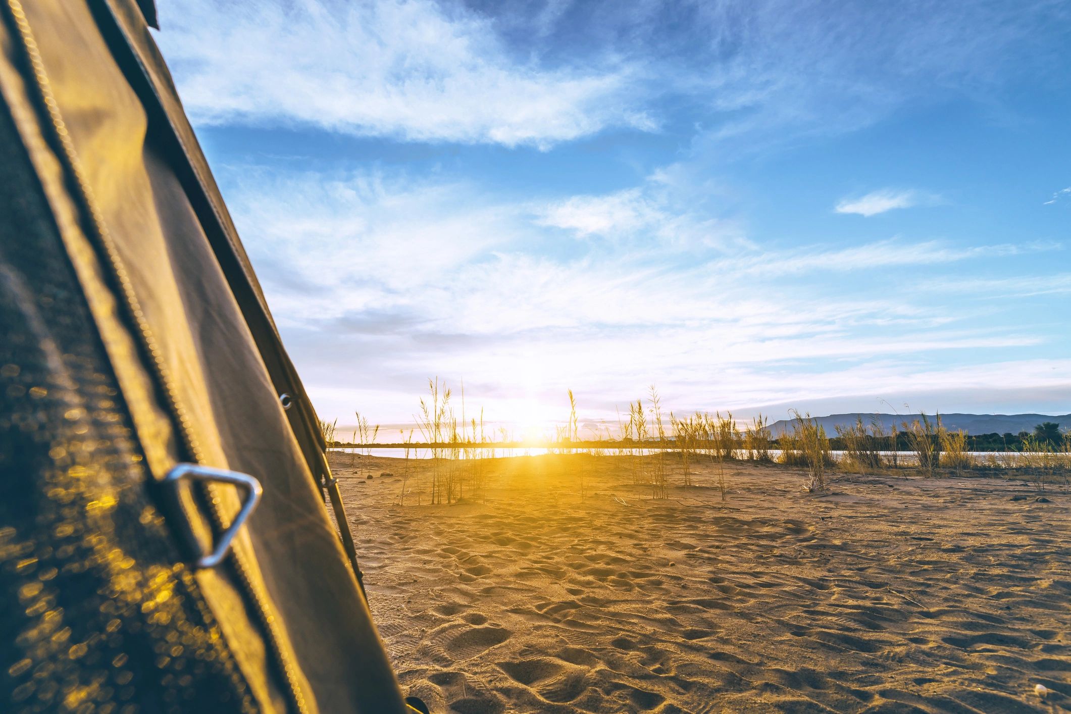 View from a canvas tent at sunset over a campsite
