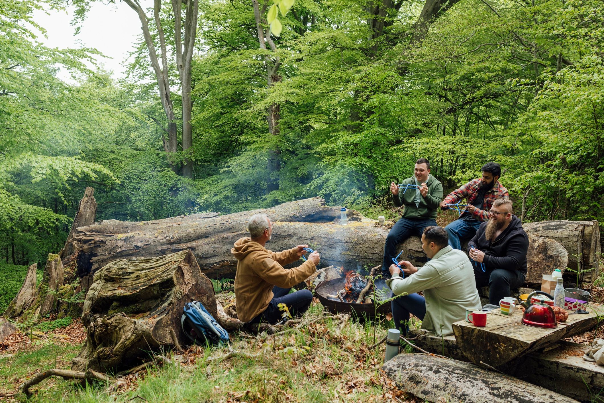 Campers gathered around a woodland fire learning outdoor skills