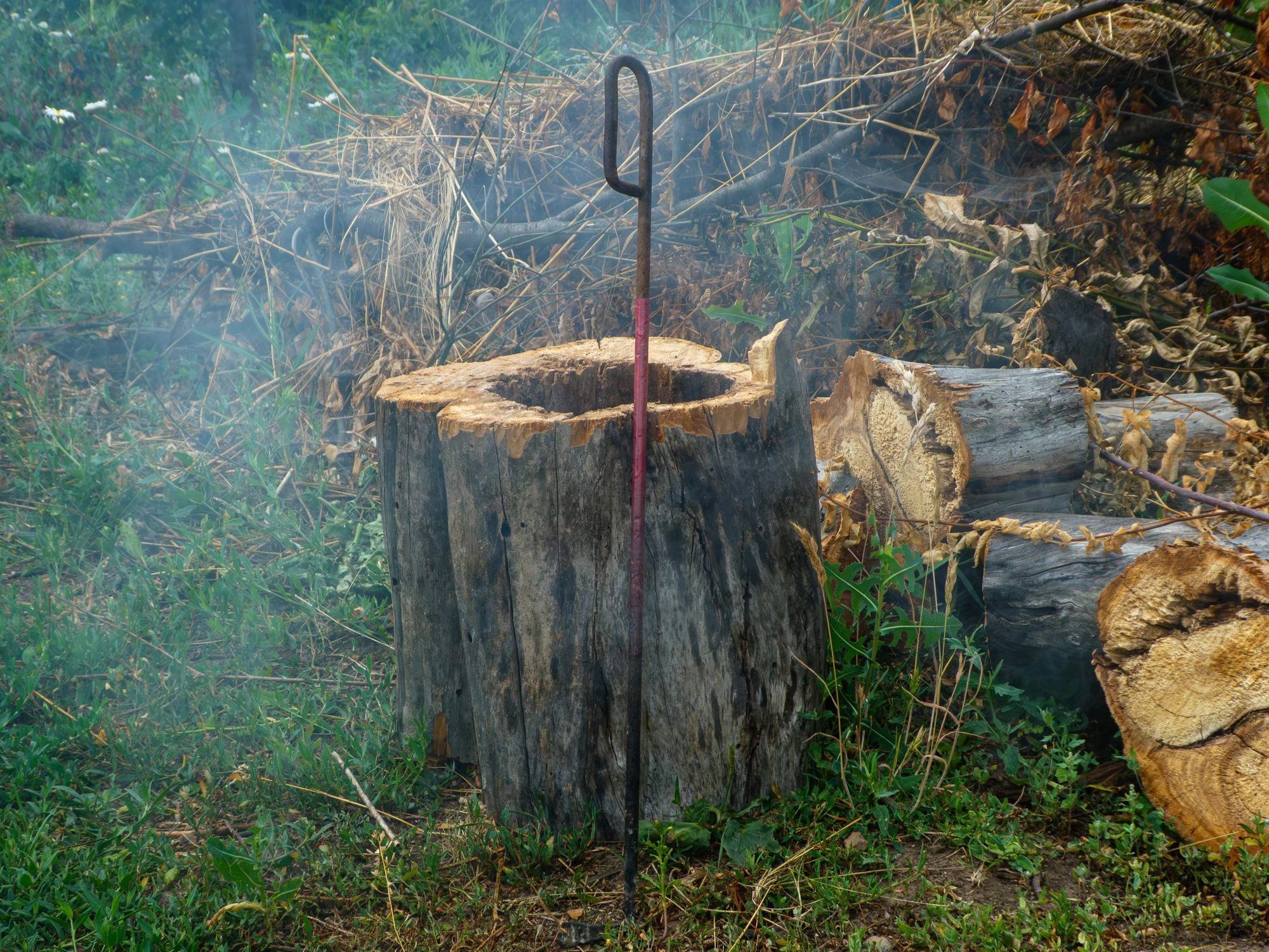 Metal fire tool outdoors near smoke and wood